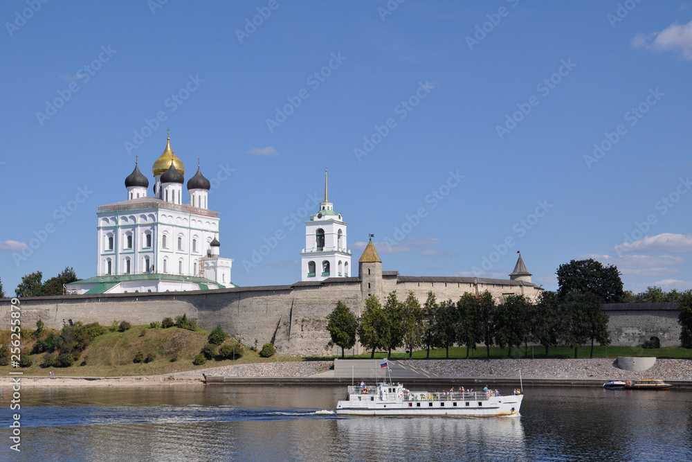 View of the Trinity Cathedral in the Pskov Kremlin from the Great River, on which the ship sails on a summer day, Russia.