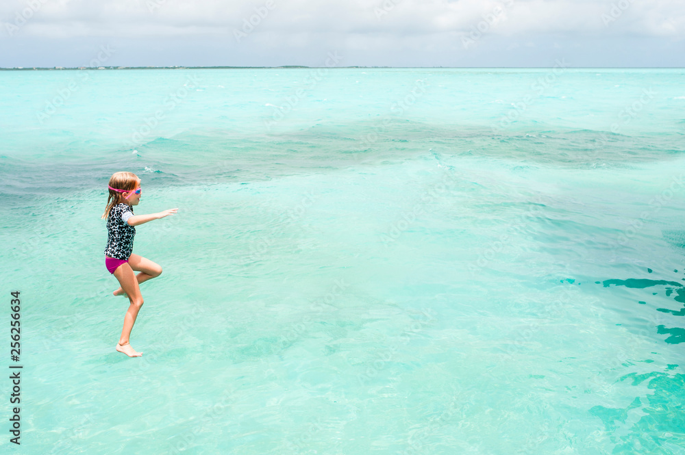 High angle view of girl jumping into sea against cloudy sky High angle view of girl jumping into sea against cloudy sky