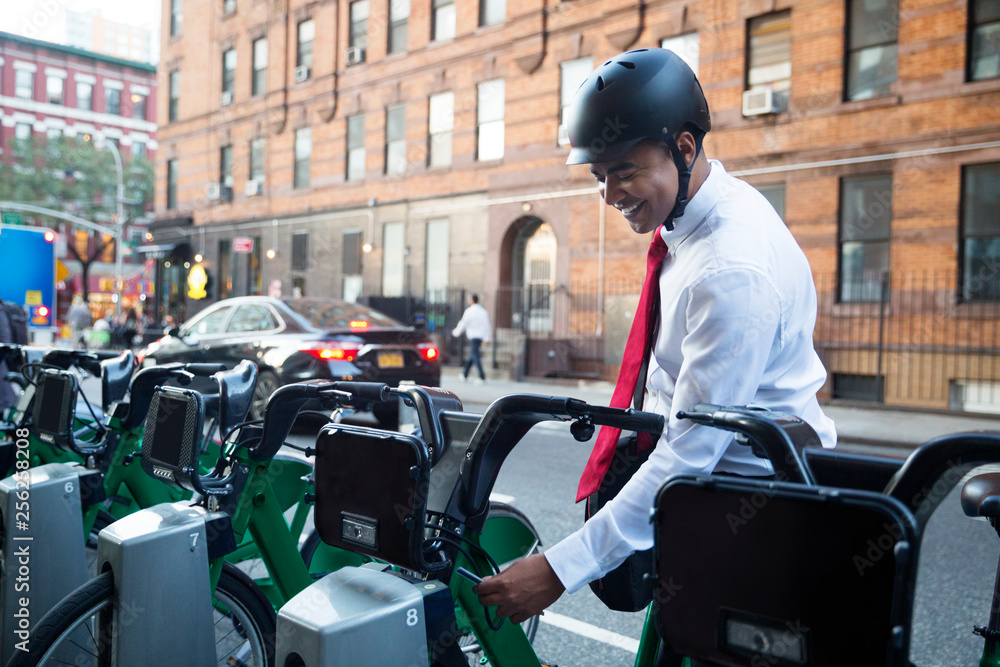 Businessman removing bicycle from rack while standing at parking lot Businessman removing bicycle from rack while standing at parking lot