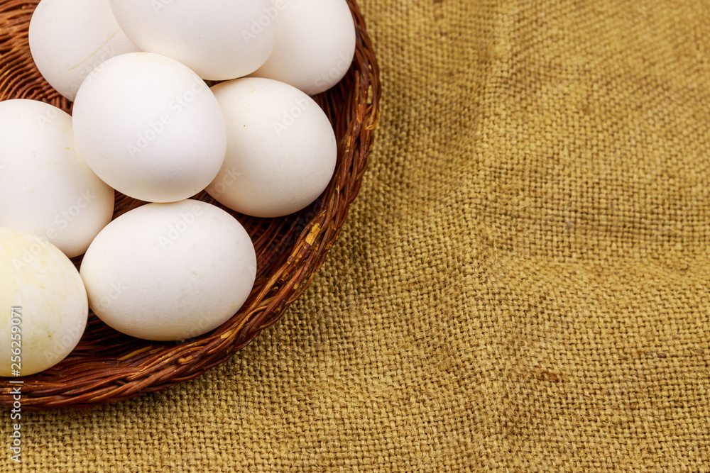 White chicken eggs in wicker basket on sackcloth background White chicken eggs in wicker basket on sackcloth background