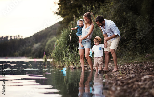 A young family with two toddler children outdoors by the river in summer. photo
