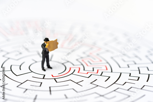 Miniature people, businessman in the labyrinth or maze figuring out the way out. Business concept, finding solution, strategic, and business opportunity. photo