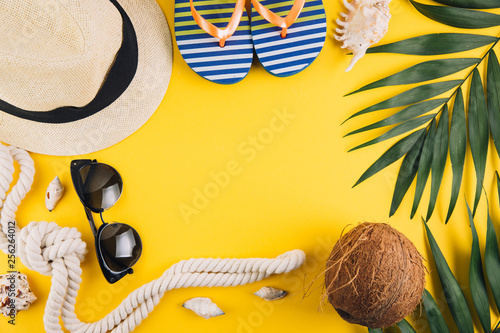 Summer concept. Travel accessories: a straw hat, a coconut, a rope shells, slippers and sunglasses.
