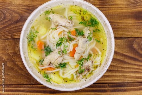 Chicken soup with noodles and vegetables on wooden table. Top view