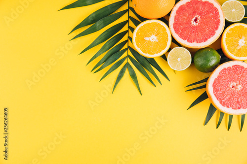 Fototapeta Naklejka Na Ścianę i Meble -  Summer fruits. Tropical palm leaves, lime, grapefruit and orange on yellow background. Flat lay, top view, copy space