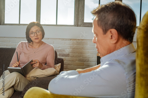 Attentive dark-haired woman in clear glasses asking questions