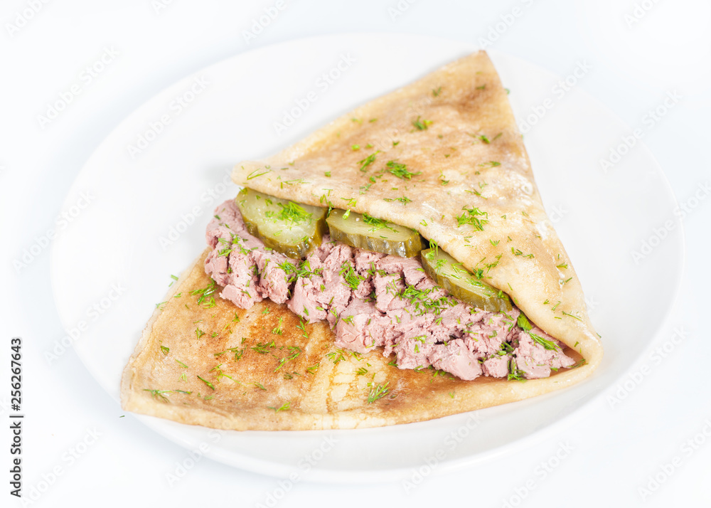 Thin delicious pancake with meat pate and cucumber on white Thin delicious pancake with meat pate and cucumber on white