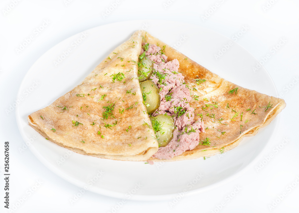 Thin delicious pancake with meat pate and cucumber on white Thin delicious pancake with meat pate and cucumber on white
