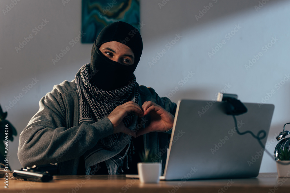 Criminal in black mask showing heart sign at webcam Criminal in black mask showing heart sign at webcam