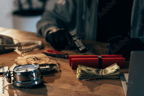 Partial view of terrorist sitting at table with money and weapon photo
