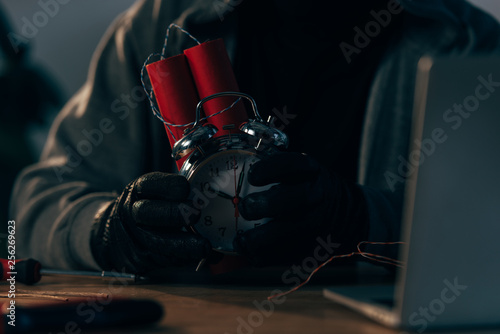 Partial view of criminal in leather gloves holding bomb