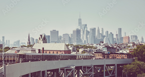 Retro toned picture of a subway train with New York City skyline, USA. photo