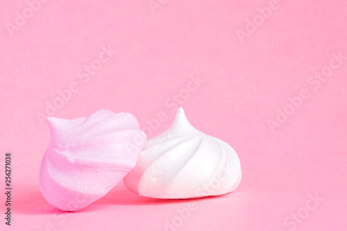 White and pink twisted meringues on pink background. French dessert prepared from whipped with sugar and baked egg whites. Greeting card with copy space