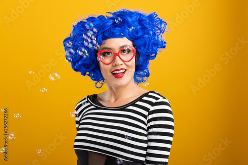 Fun portrait of pretty Asian woman with bright blue wig and red heart shaped glasses