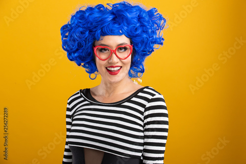 Fun portrait of pretty Asian woman with bright blue wig and red heart shaped glasses