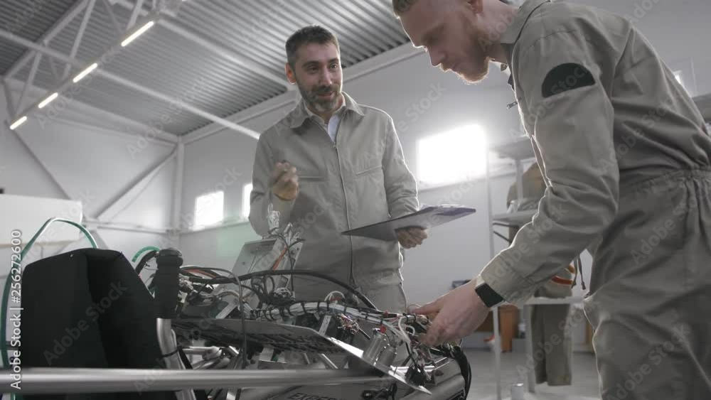 Mature mechanic instructing young specialist Mature mechanic instructing young specialist