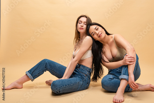 dreamy young women sitting in blue jeans and bras, body positivity concept