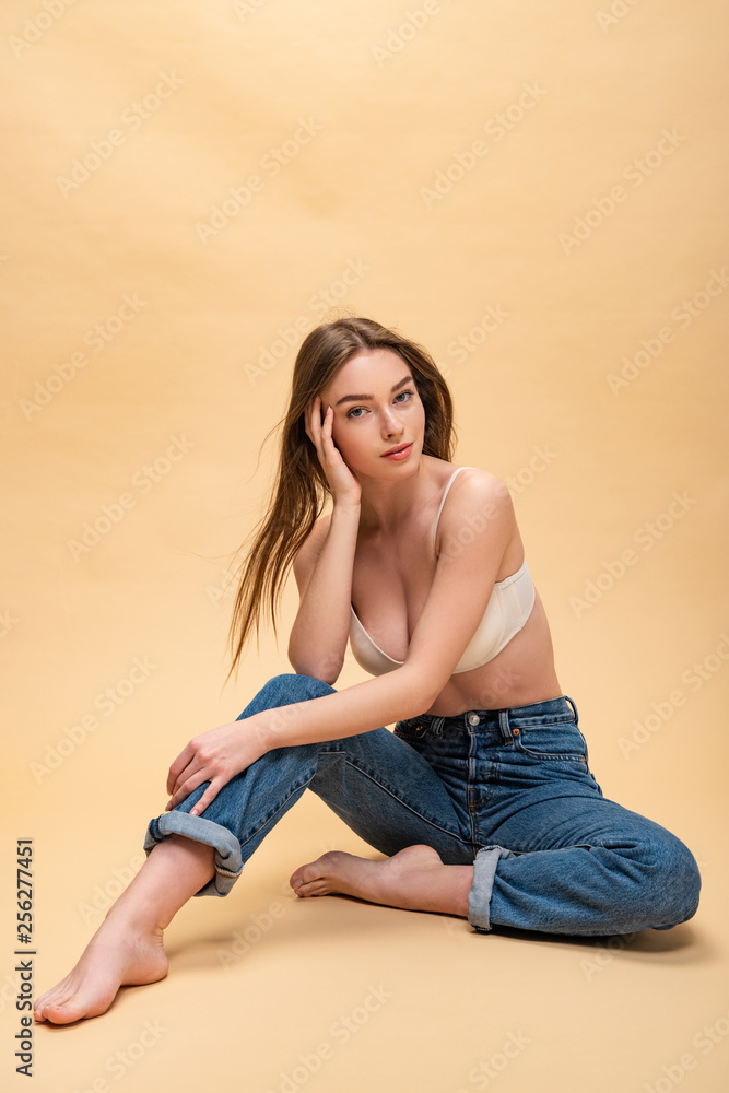 happy pretty girl in blue jeans and bra sitting and looking at camera happy pretty girl in blue jeans and bra sitting and looking at camera