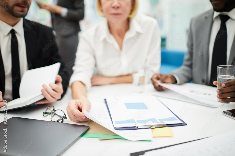 Cropped shot of unrecognizable businesswoman reading documents during meeting in office, copy space background Cropped shot of unrecognizable businesswoman reading documents during meeting in office, copy space background