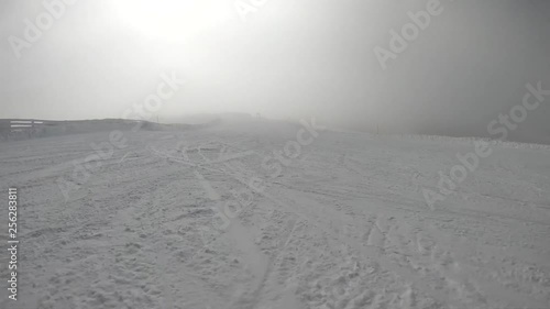 Snowboarder riding fast down a slope piste during winter time with foggy cloudy weather. Camera first person view. Lot of snow. Ylläs Lapland Finland