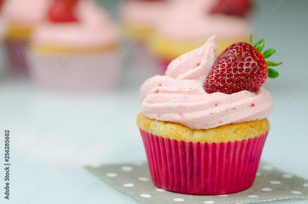 Delicious pink strawberry cupcake with a strawberry. Cupcakes and pink icing with a strawberries on top