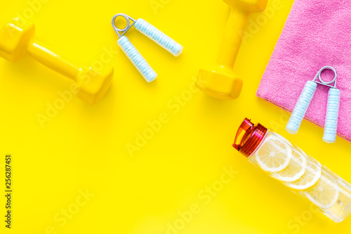 workout with bars, bottle of water and wrist builder yellow background top view mockup