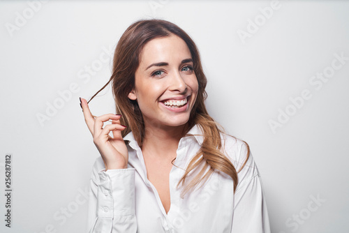 Portrait of laughing young woman twirling strand of hair