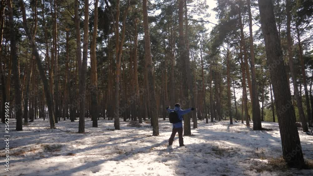 A man is a tourist in a pine forest with a backpack. A young traveler in a hike in the winter. Winter sport activity. Man hiking in the forest. A man is a tourist in a pine forest with a backpack. A young traveler in a hike in the winter. Winter sport activity. Man hiking in the forest.