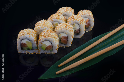 sushi roll with sesame on black background