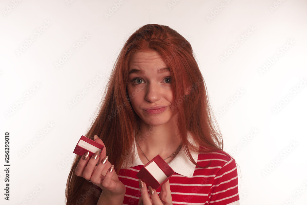 The portrait of an young redhead lady with a gift box in her hands isolated over white background posing The portrait of an young redhead lady with a gift box in her hands isolated over white background posing
