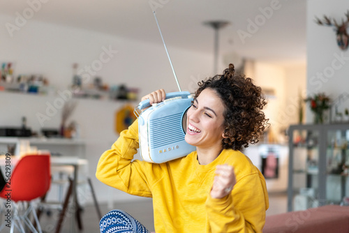 Carefree woman listening to music with portable radio at home photo
