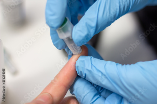 Diabetes patient measuring glucose level blood test using ultra mini glucometer and small drop of blood from finger and test strips isolated on a white background