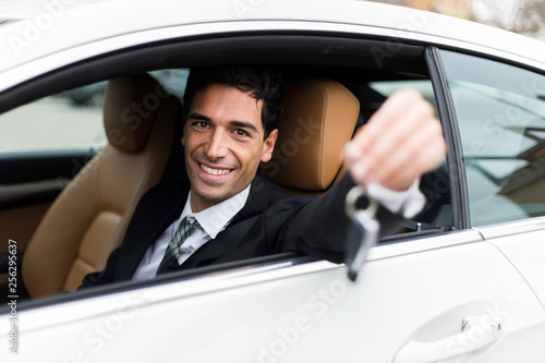 Young businessman smiling in his new car showing car keys © Minerva Studio