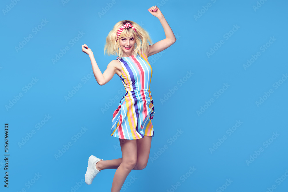Young fashionable girl Smiling jump in Studio. Beautiful easy-going blonde woman in Stylish summer dress having fun, makeup, Trendy sneakers. Cheerful happy model, funny fashion concept Young fashionable girl Smiling jump in Studio. Beautiful easy-going blonde woman in Stylish summer dress having fun, makeup, Trendy sneakers. Cheerful happy model, funny fashion concept