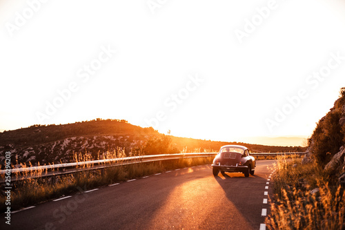 Spain, classic car driving on road during sunset photo