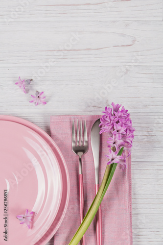 Pink rustic place setting with purple hyacinth flower and linen napkin on white wooden background
