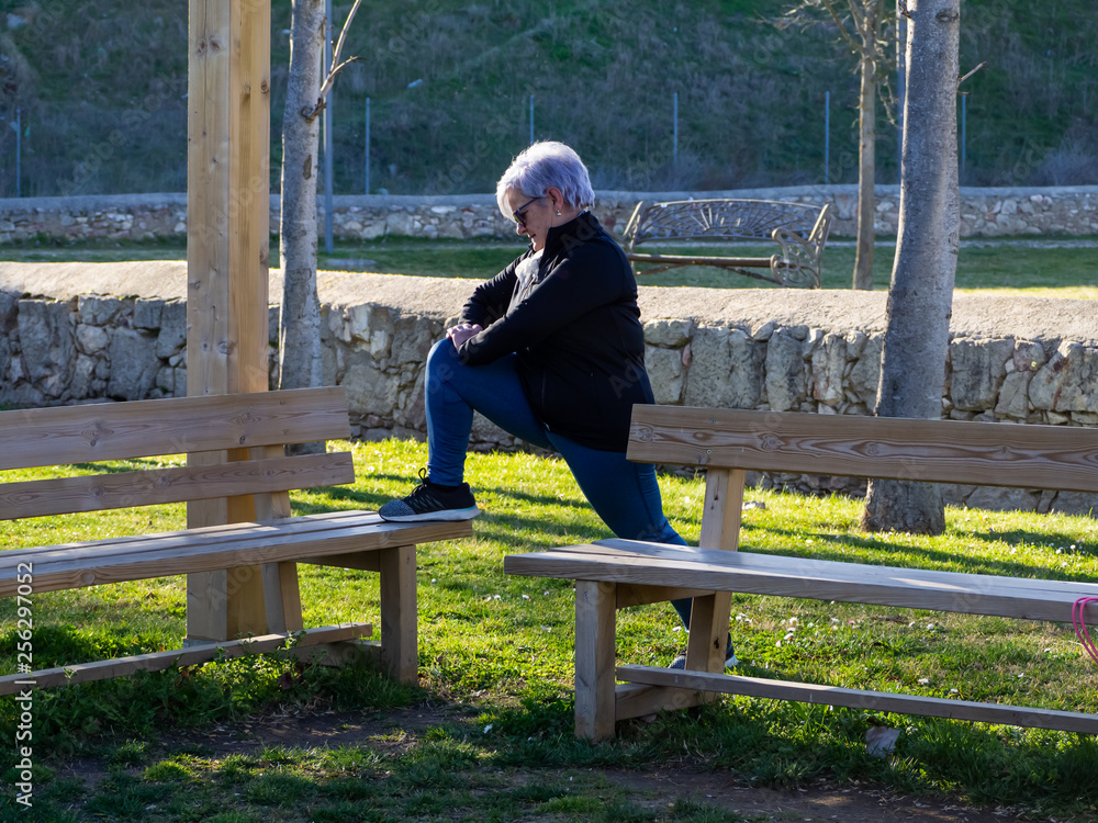 A senior woman with white hair practicing gymnastics in an urban park A senior woman with white hair practicing gymnastics in an urban park