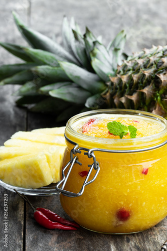Картината върху платно Homemade pineapple and chili pepper chutney in glass jar on gray table