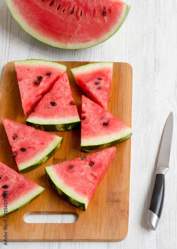 Chopped water melon on bamboo board on a white wooden table, high angle view. Summer food.