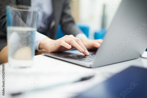 Closeup of unrecognizable businesswoman typing on keyboard while using laptop in office, copy space © Seventyfour