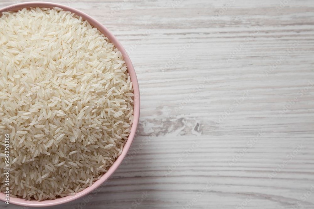 Top view, dry white rice basmati in a pink bowl over white wooden table, top view. Flat lay, overhead, from above. Copy space. Top view, dry white rice basmati in a pink bowl over white wooden table, top view. Flat lay, overhead, from above. Copy space.
