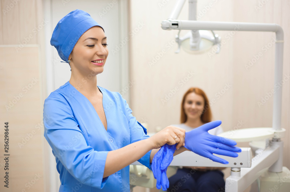 Obraz premium A young female doctor preparing herself for working, putting on protective gloves.
