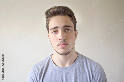 Portrait of young handsome man looking at camera isolated on gray background.