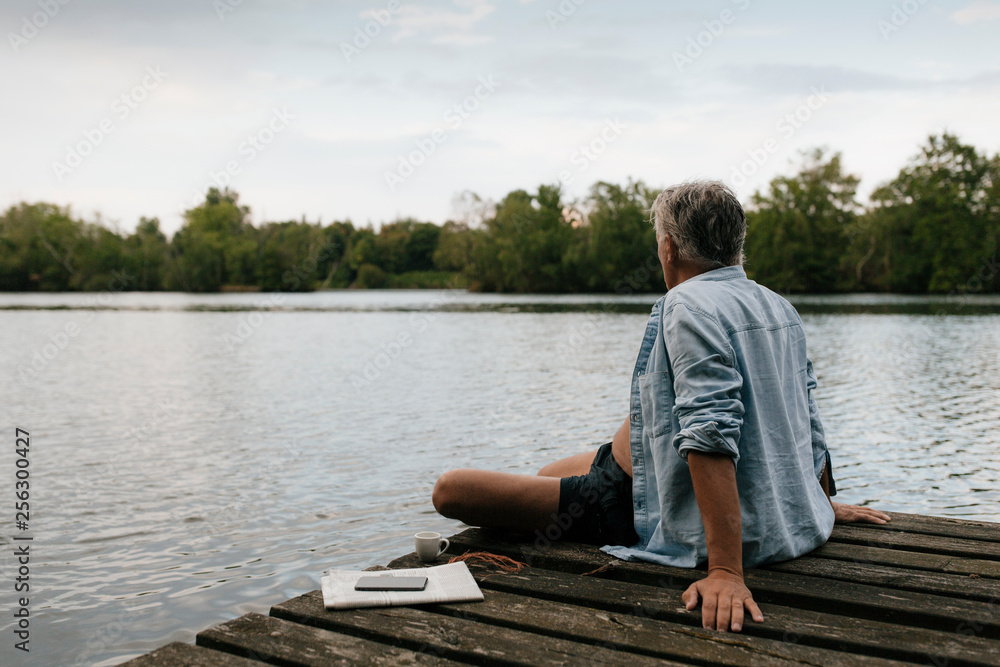 Senior man sitting on jetty at a lake Senior man sitting on jetty at a lake