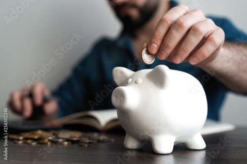 Man putting coin in piggy bank. Saving money concept.