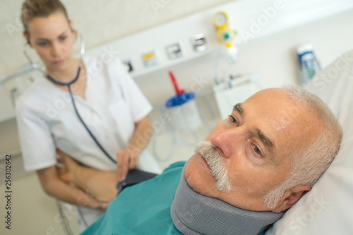 nurse taking blood pressure of mature patient wearing neck brace