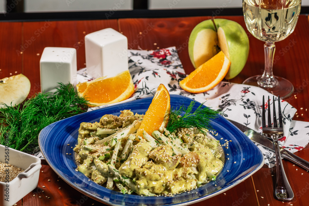 Fresh salad with chicken, orange, apple and green curry sauce. Served with white wine and cheese on the blue plate. Wooden background. horizontal view