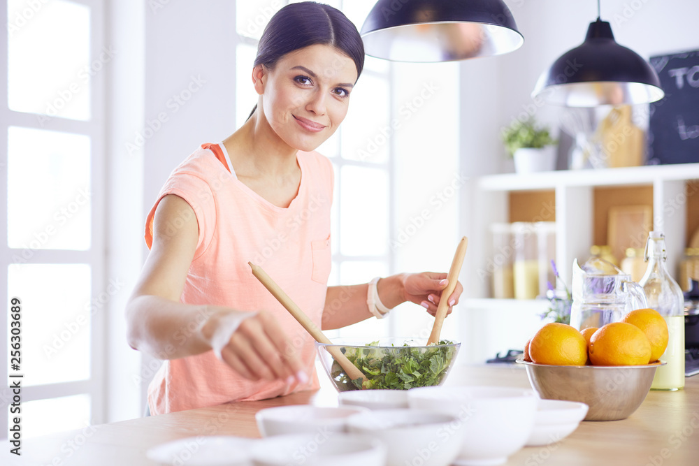 Smiling young woman mixing fresh salad in the kitchen. Smiling young woman mixing fresh salad in the kitchen.