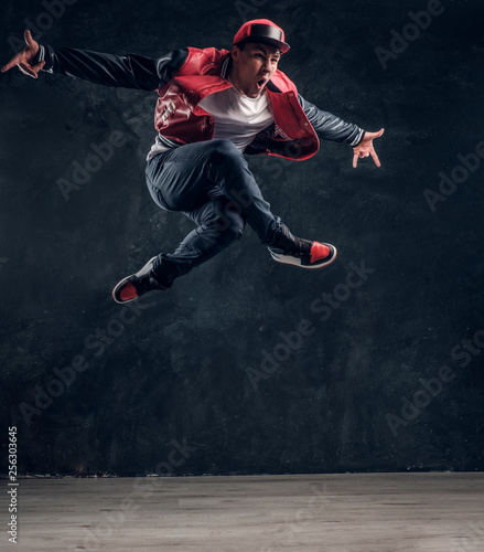 Emotional hip-hop style dancer performing dance elements. Studio photo against a dark textured wall © Fxquadro