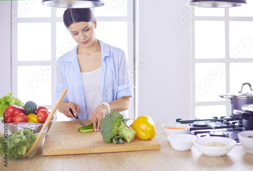 Young woman cutting vegetables in kitchen at home.